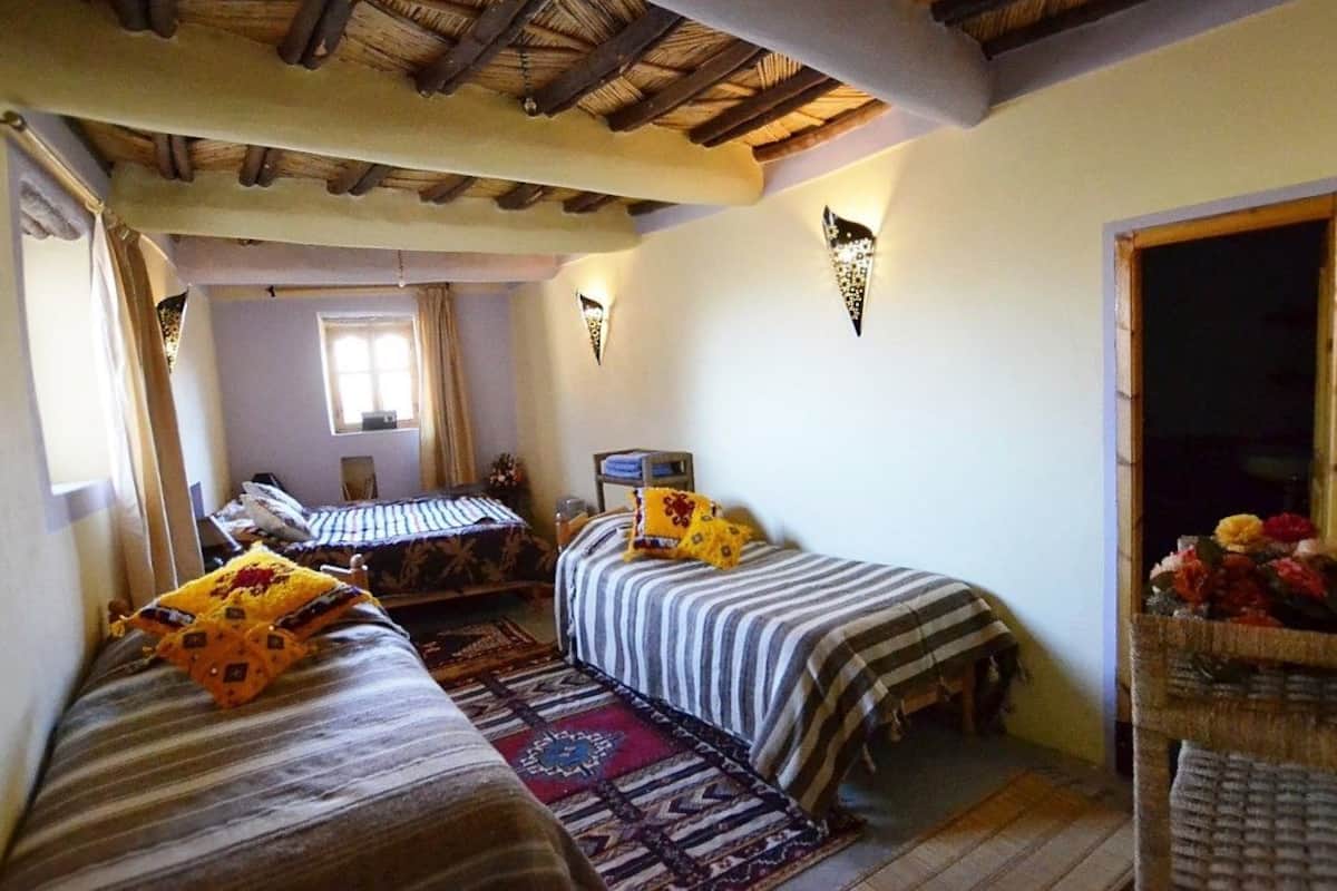 A cozy room with two beds, a window, and a rustic ceiling.