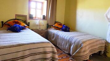 A room with two beds, a window, and a wooden ceiling.