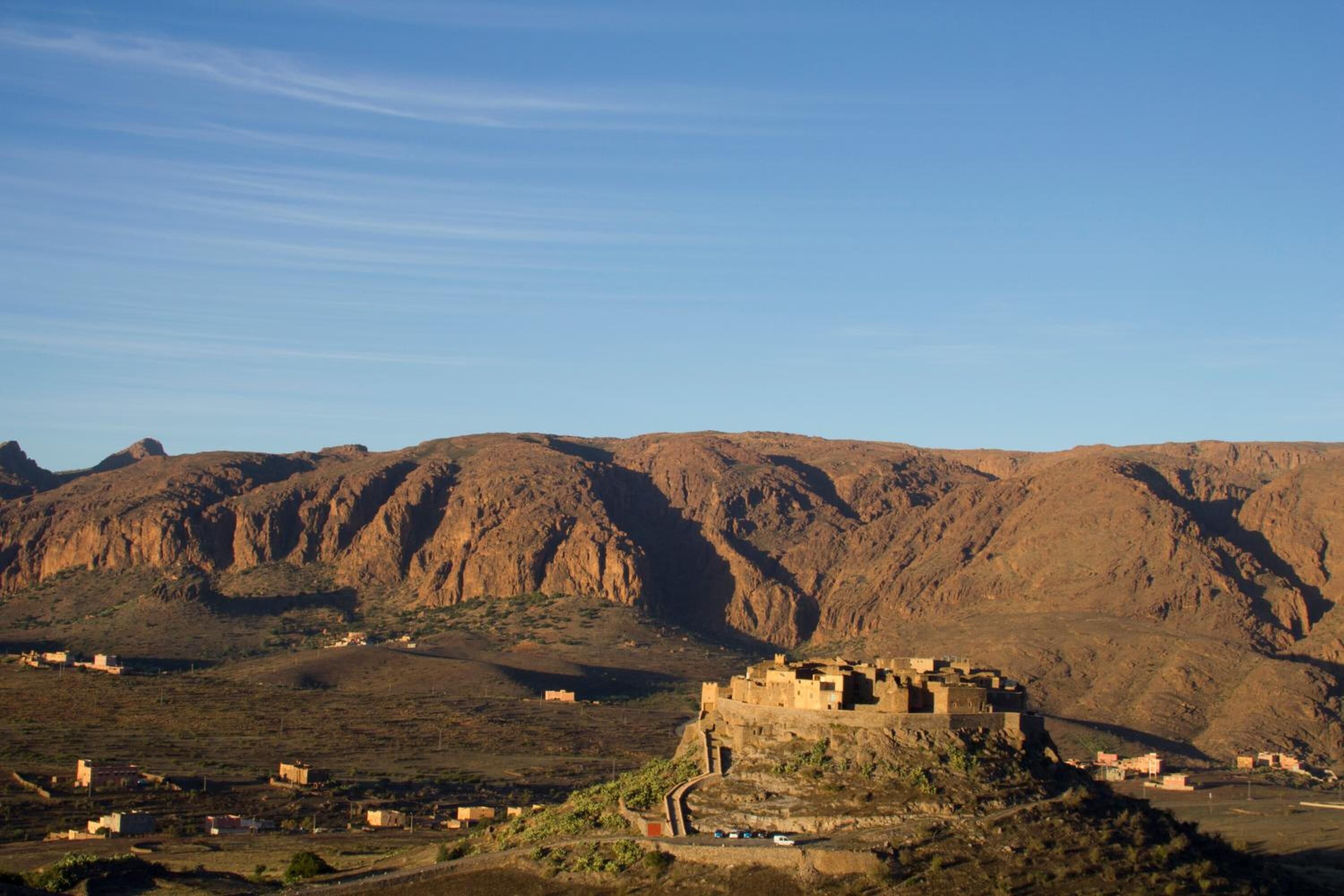 Un paisaje montañoso con una estructura fortificada rodeada de edificios más pequeños.