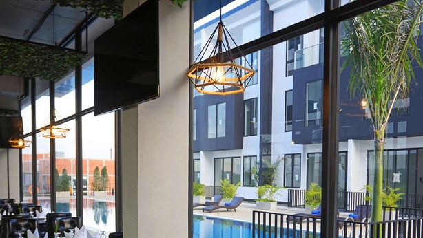 A restaurant with a pool view, large windows, and black leather seating. - Eco Garden Residences (Kandal Stueng)