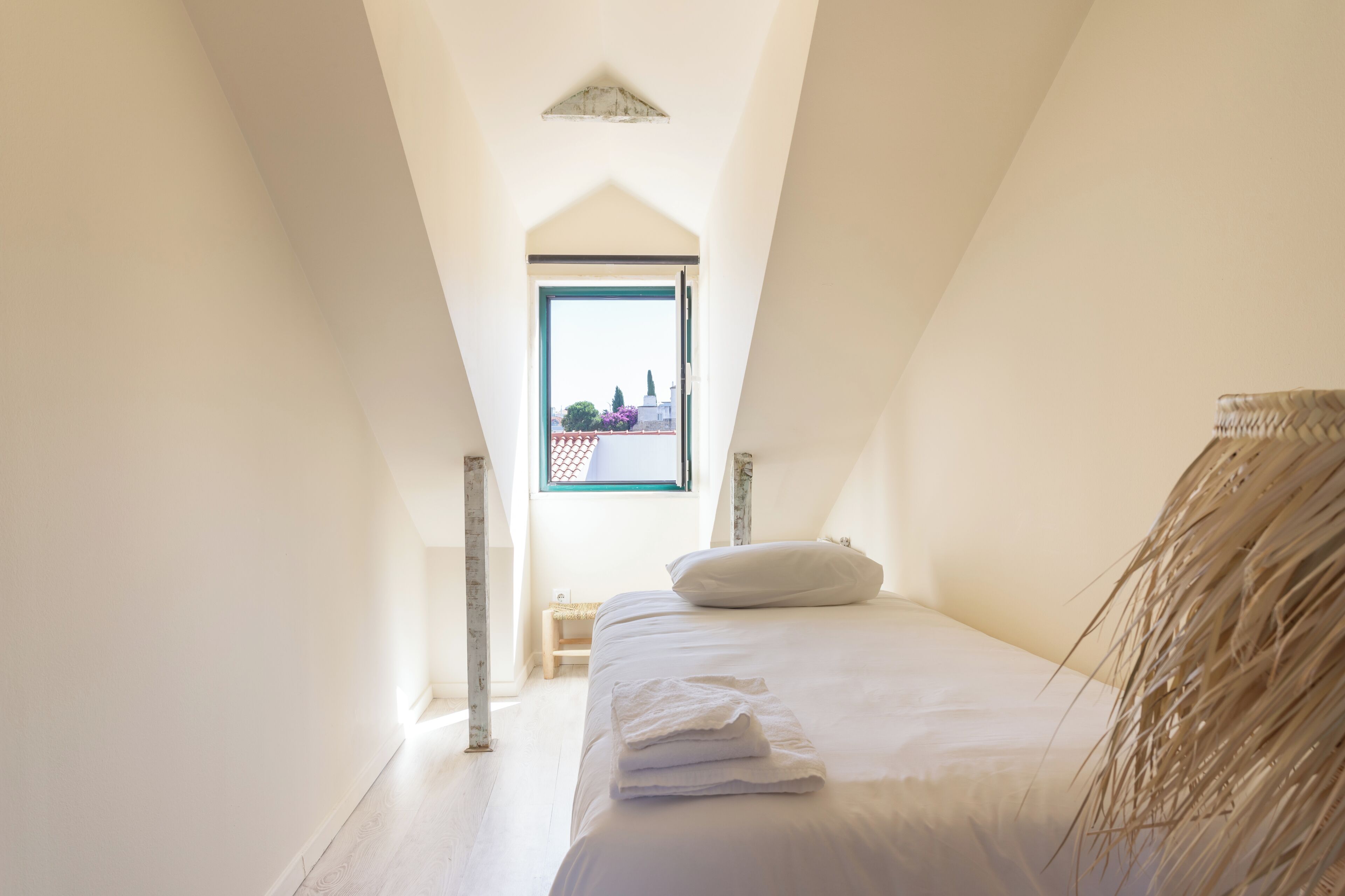 A bedroom with a bed, a window, and a view of buildings outside.