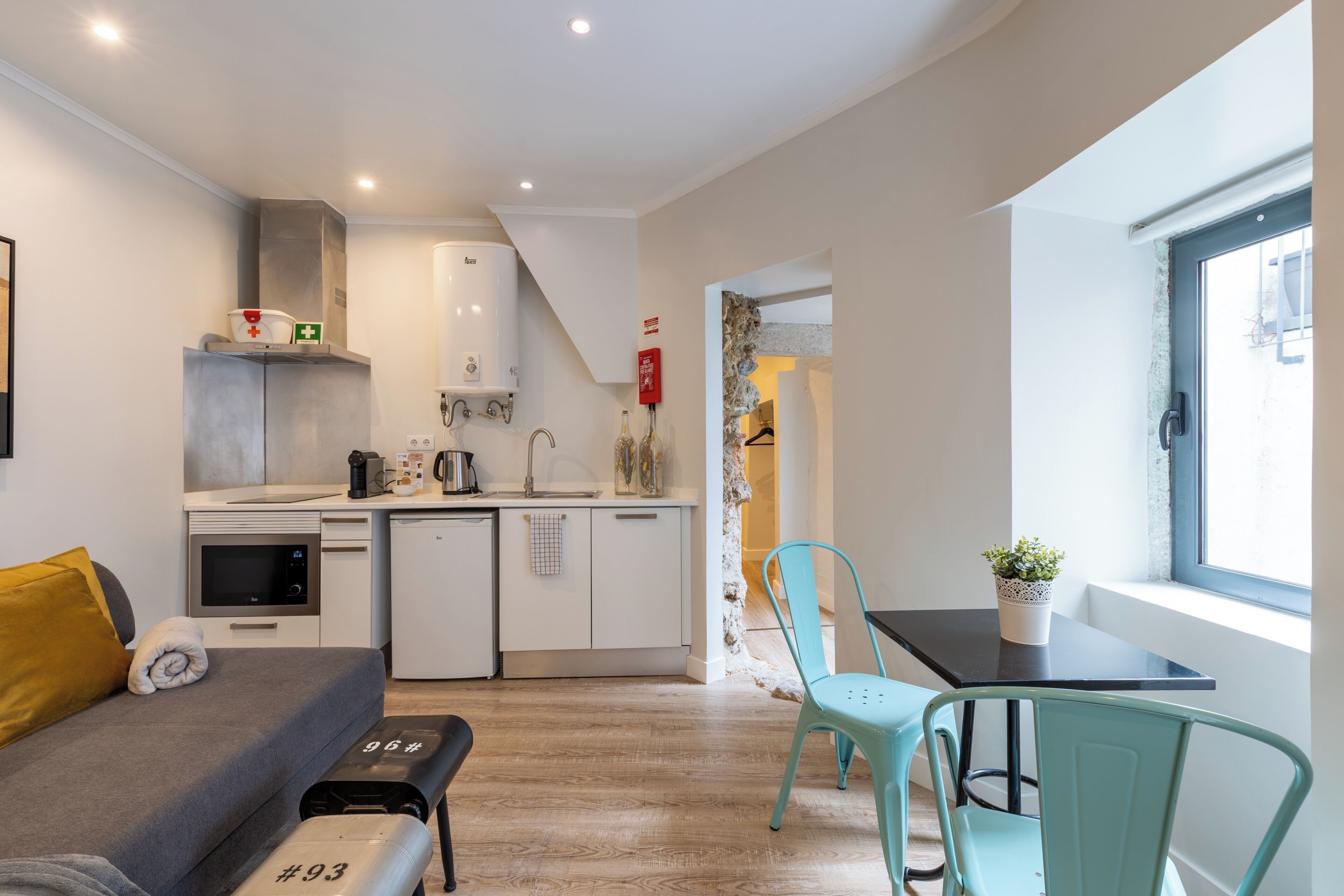 Une pièce de taille modeste comprenant un lit, un coin cuisine et un espace repas avec une table et des chaises.