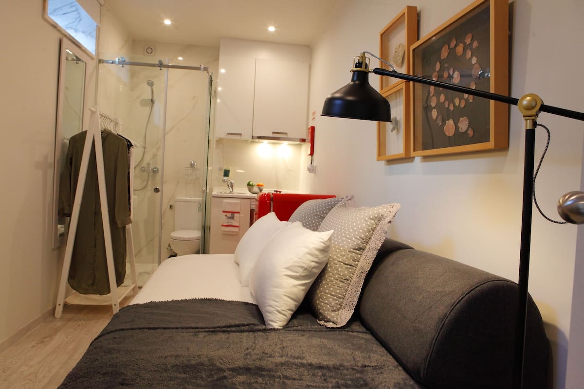 Un dormitorio con cama, mesita de noche, lámpara, ducha y retrete.