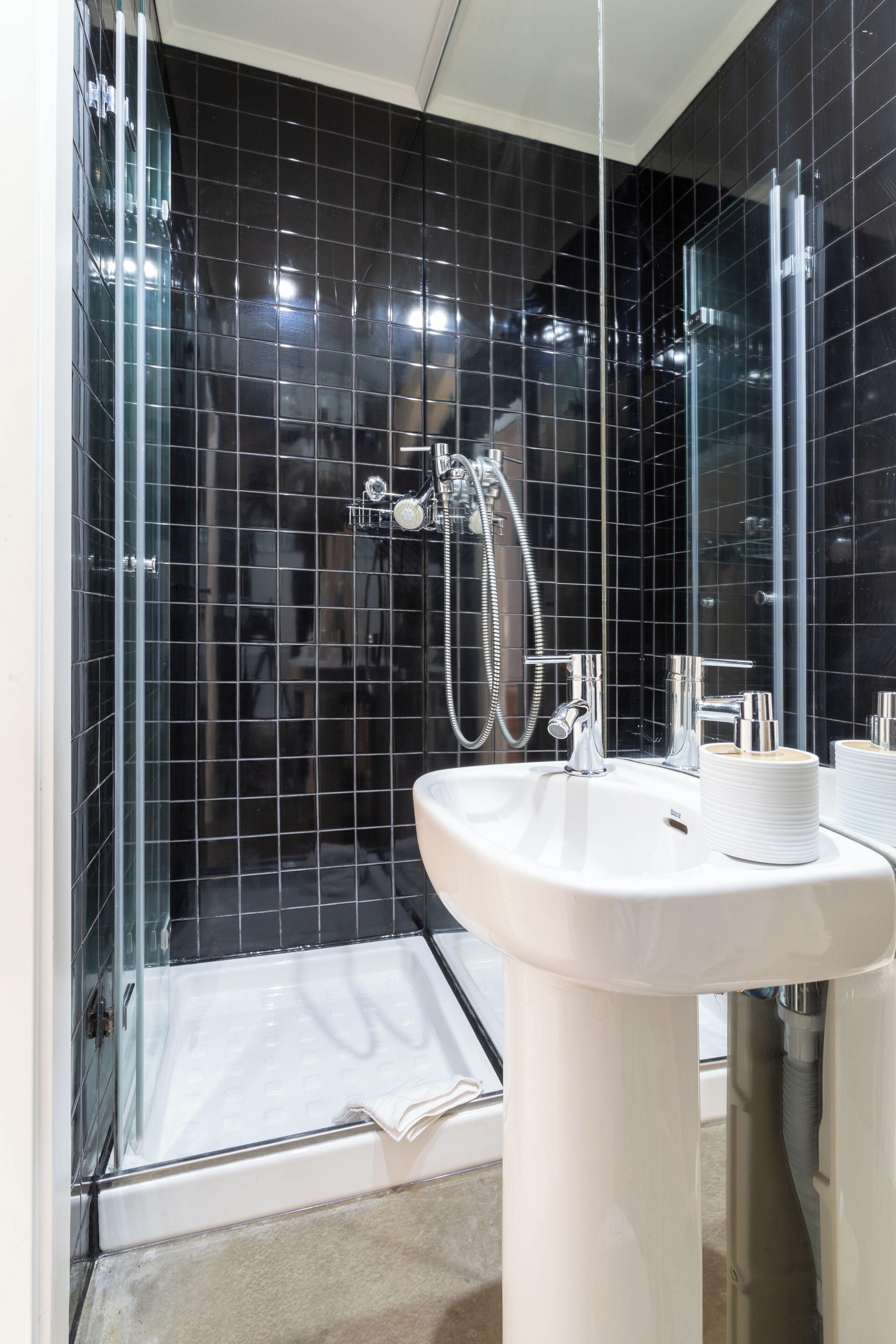 A modern bathroom with a glass shower enclosure, a white sink, and a mirror.