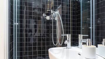 A modern bathroom with a glass shower enclosure, a white sink, and a mirror.