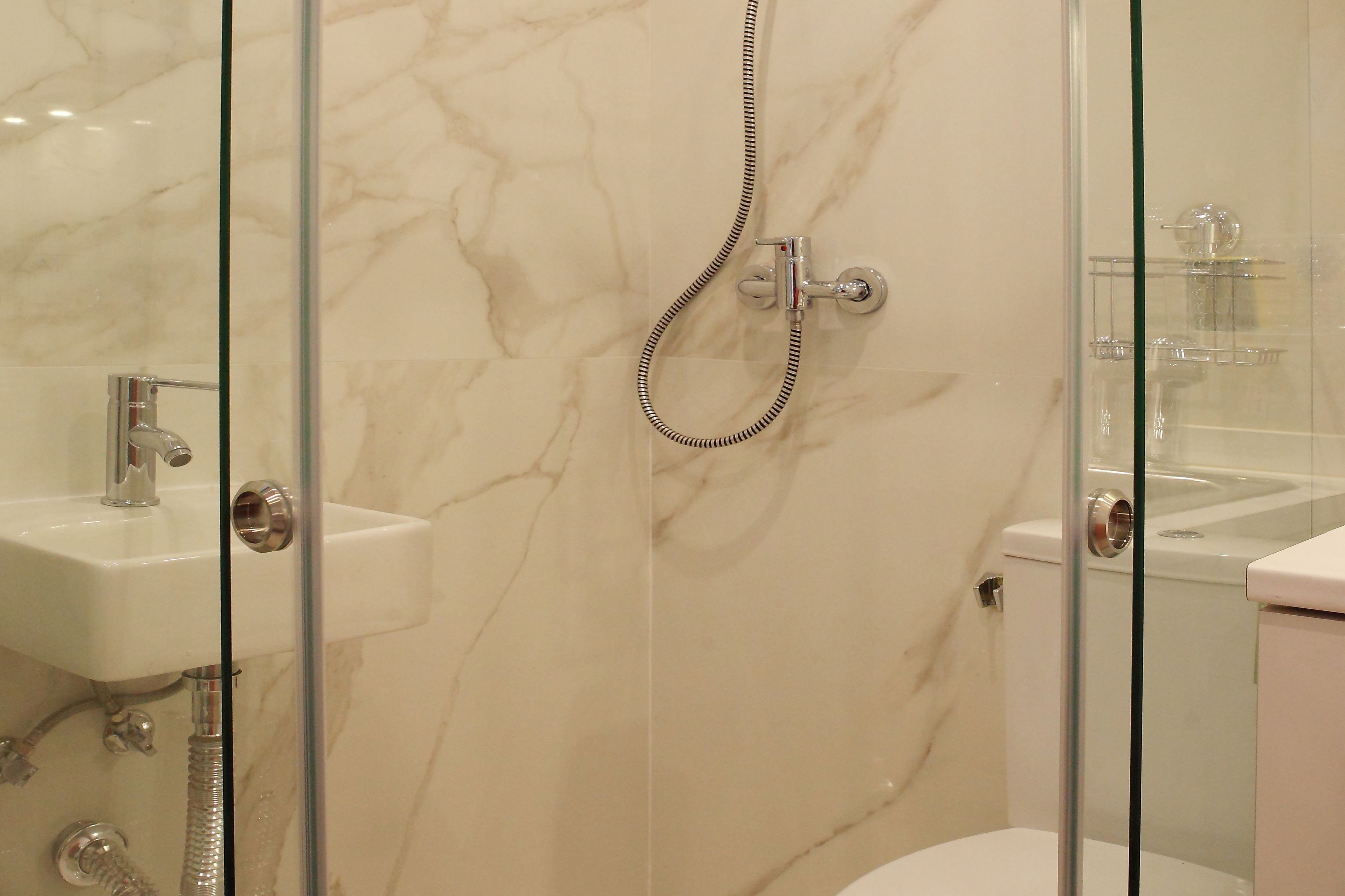 A modern bathroom with a glass-enclosed shower, a white sink, and a toilet.
