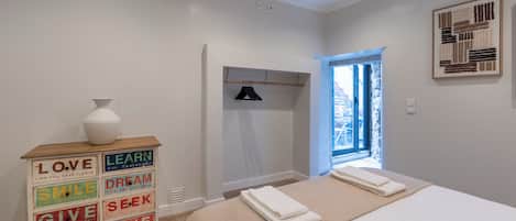 Un dormitorio con una cama, un aparador con palabras motivadoras, una ventana y una puerta.