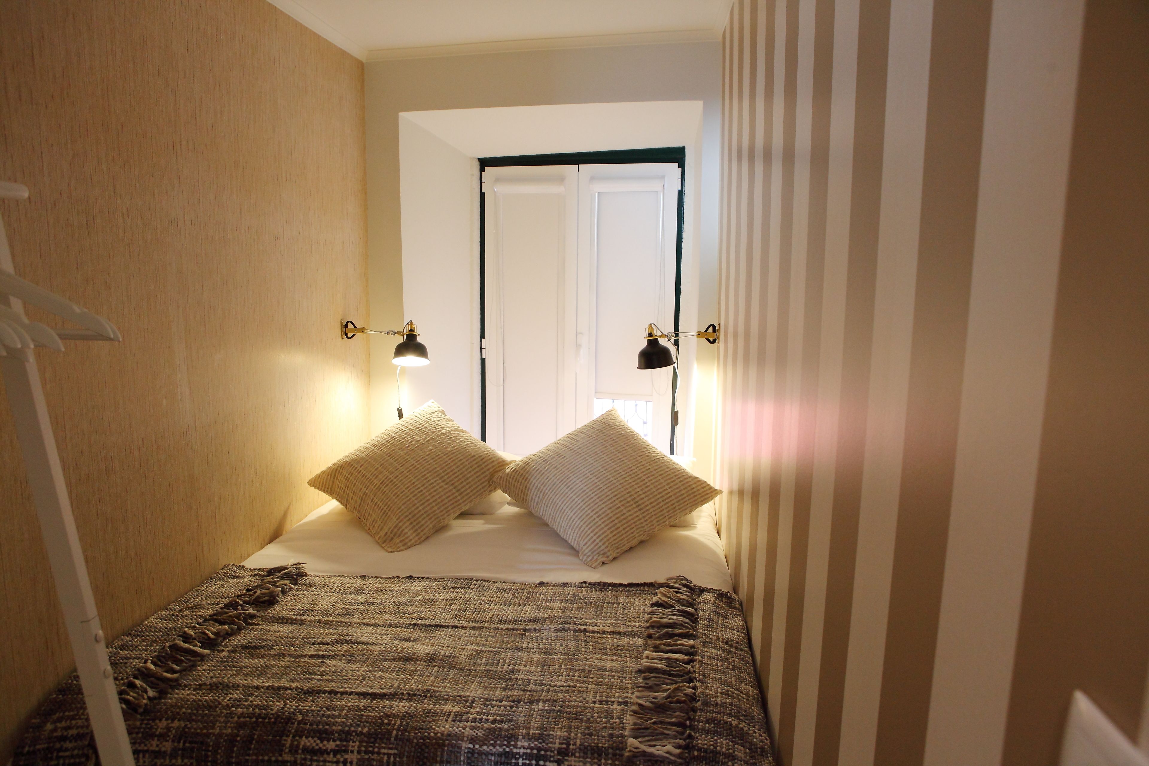 Un dormitorio con una cama, dos lámparas de noche y vistas a una puerta.