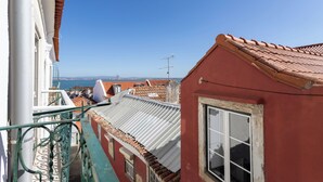 Uma rua estreita com edifícios, céu azul límpido e vista distante do mar.