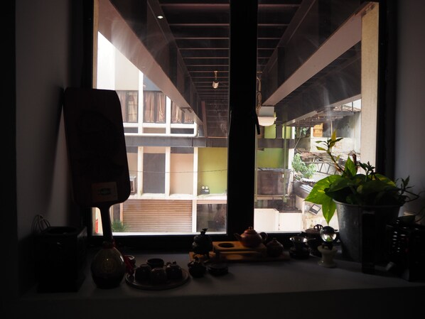 A room with a large window, a potted plant, and various tea sets on the windowsill. - Leo Backpackers Central Market (Kuala Lumpur)