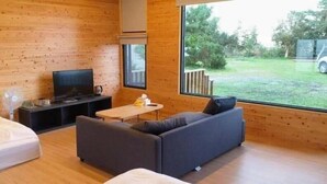A modern room with wooden walls, a sofa, a small table, and a TV. - Shen Shan Lin Nai B&B (Zhushan)
