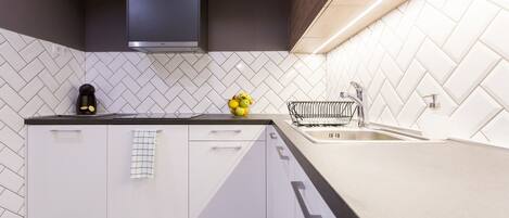 Een moderne keuken met witte kasten, een zwart aanrecht en een backsplash met een herringbone patroon.