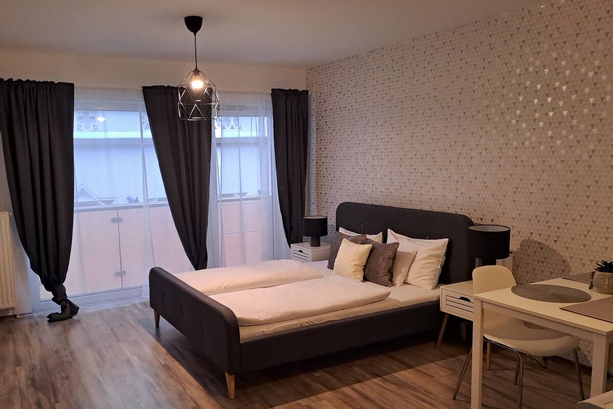 Ein modernes Schlafzimmer mit Bett, Nachttischen, Schreibtisch und Stuhl.