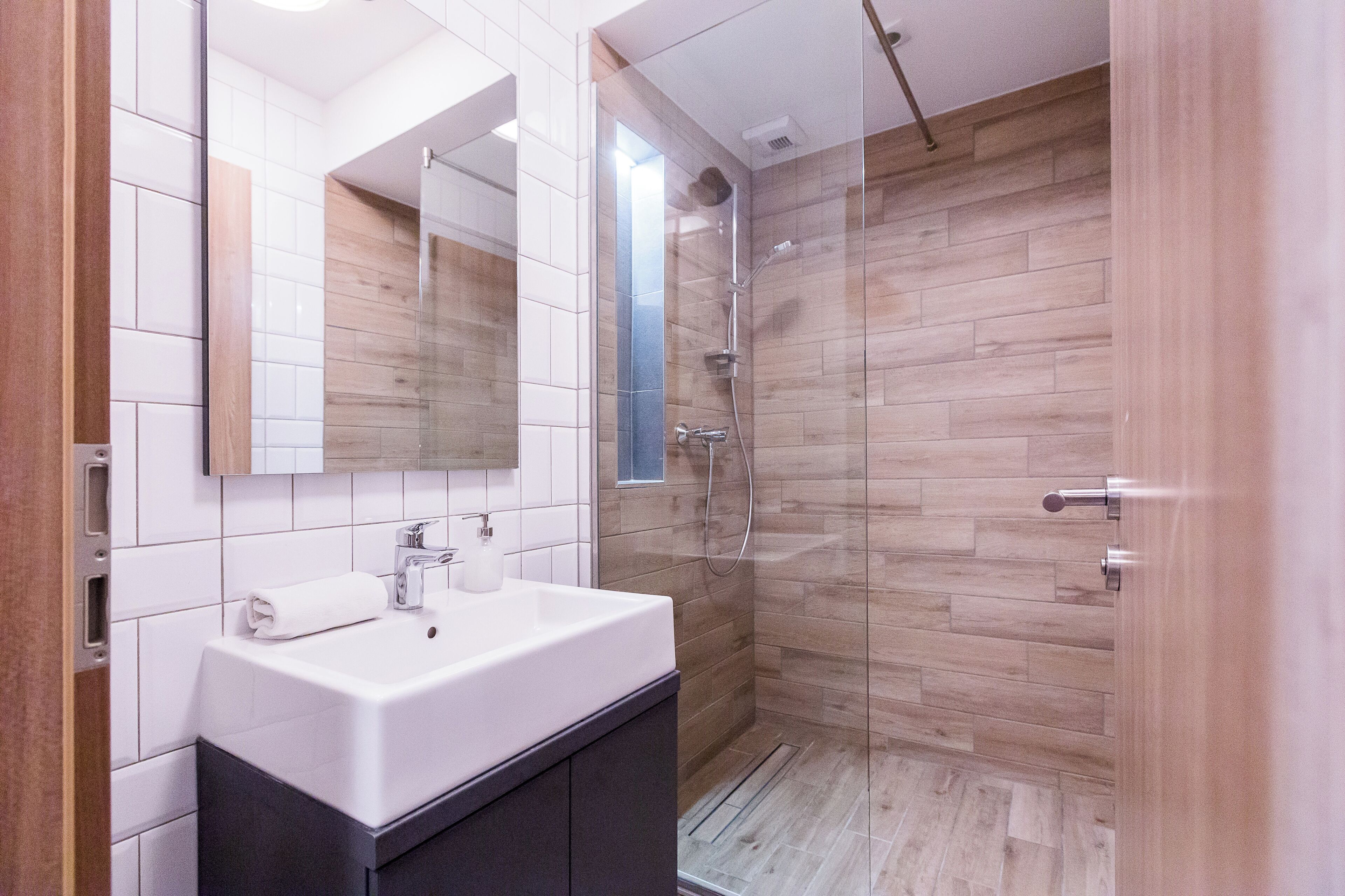 Un baño moderno con cabina de ducha de vidrio, un lavabo blanco y un espejo encima.