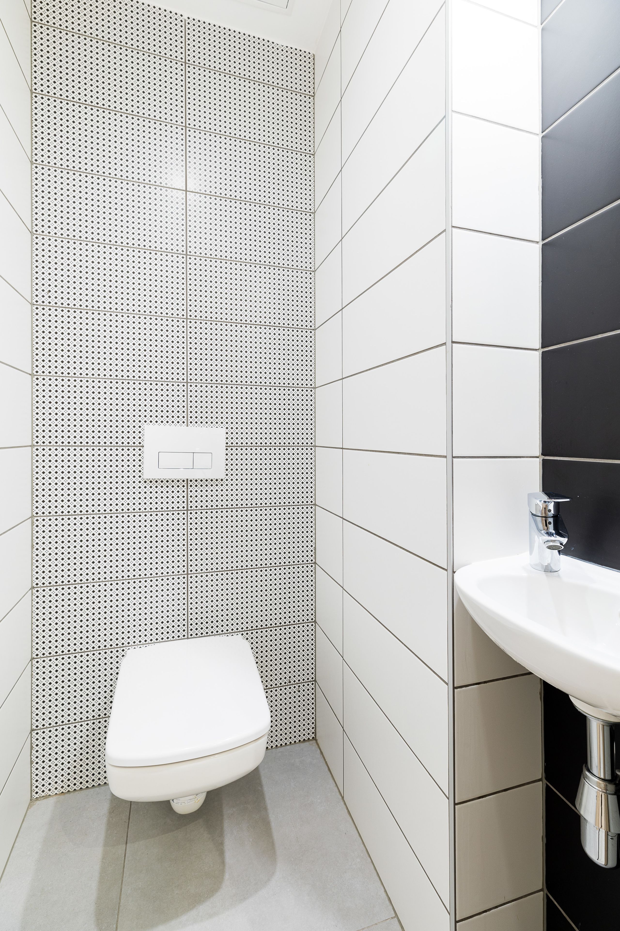A bathroom with a white toilet, a sink, and tiled walls.