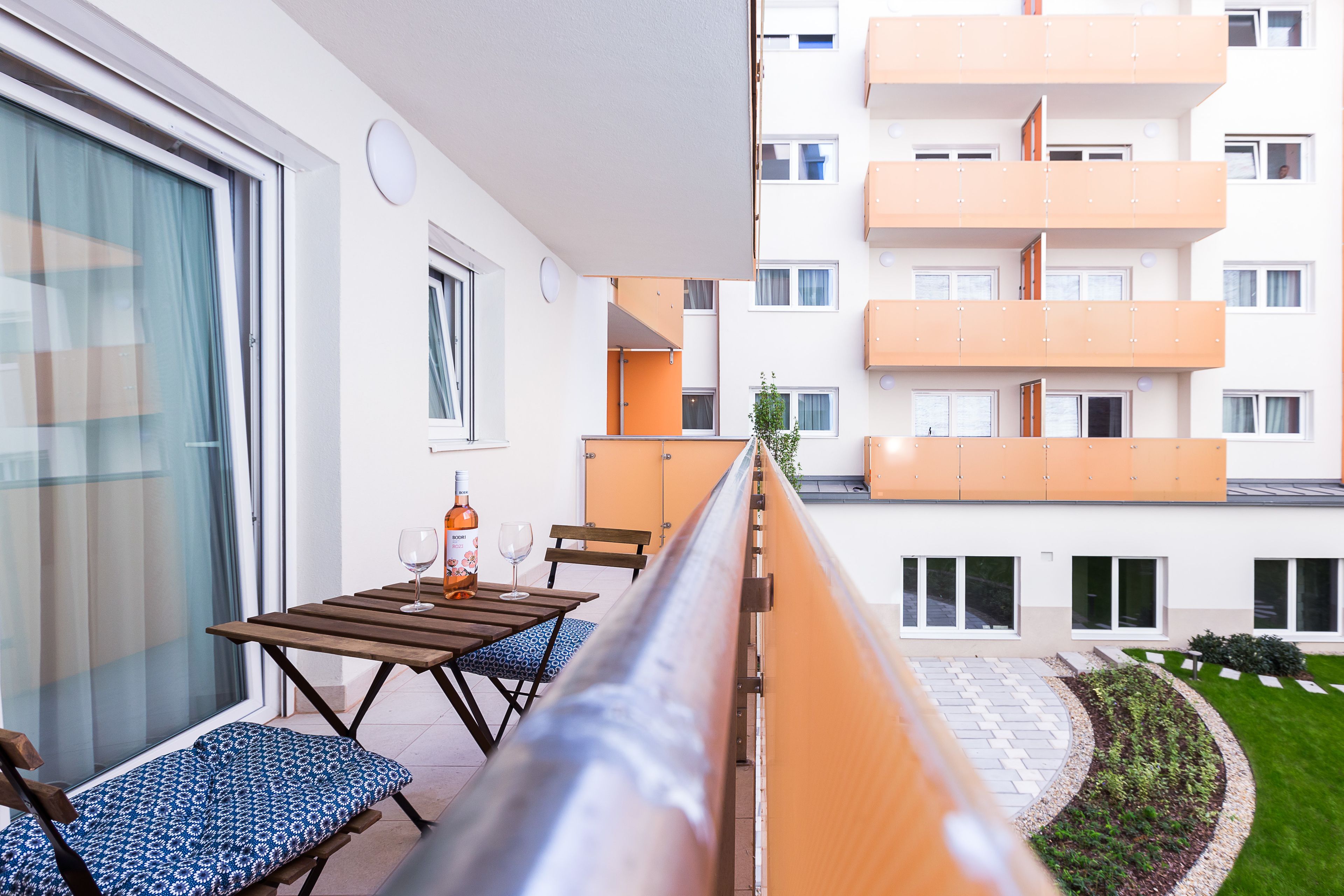 En balkon med et bord og stole, en vinflaske og et glas.