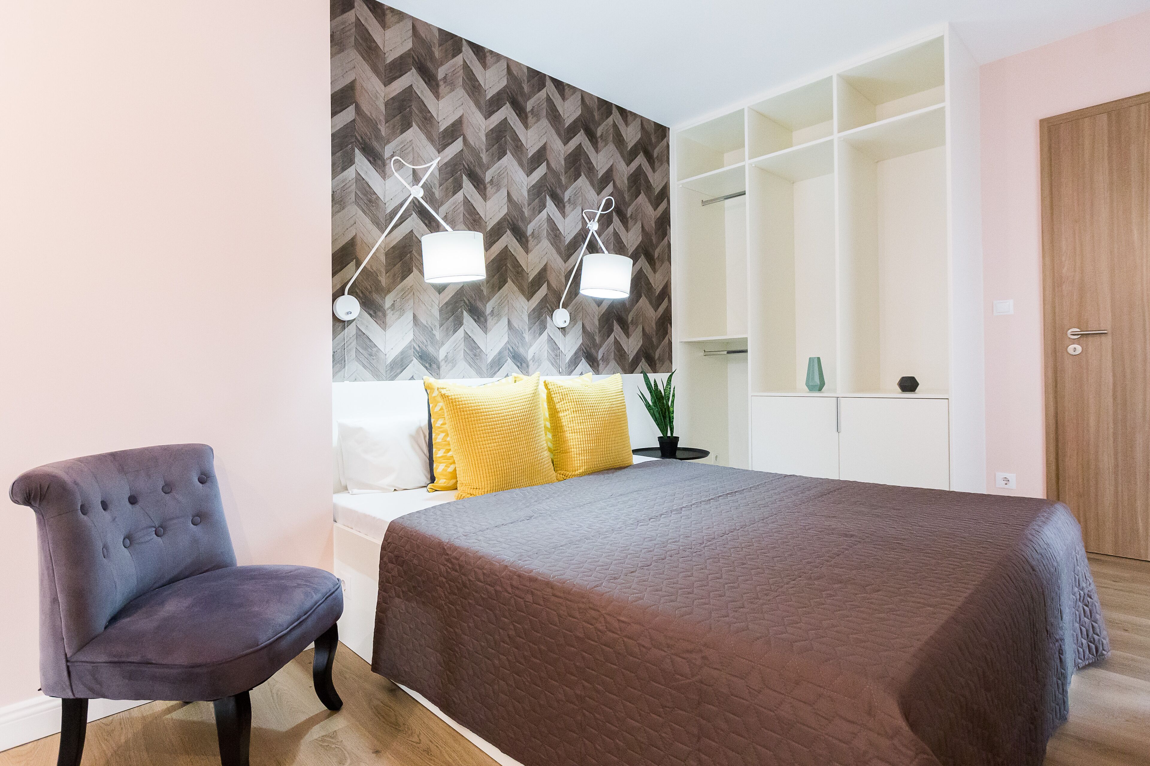Un dormitorio con cama, una silla, un armario y un espejo.