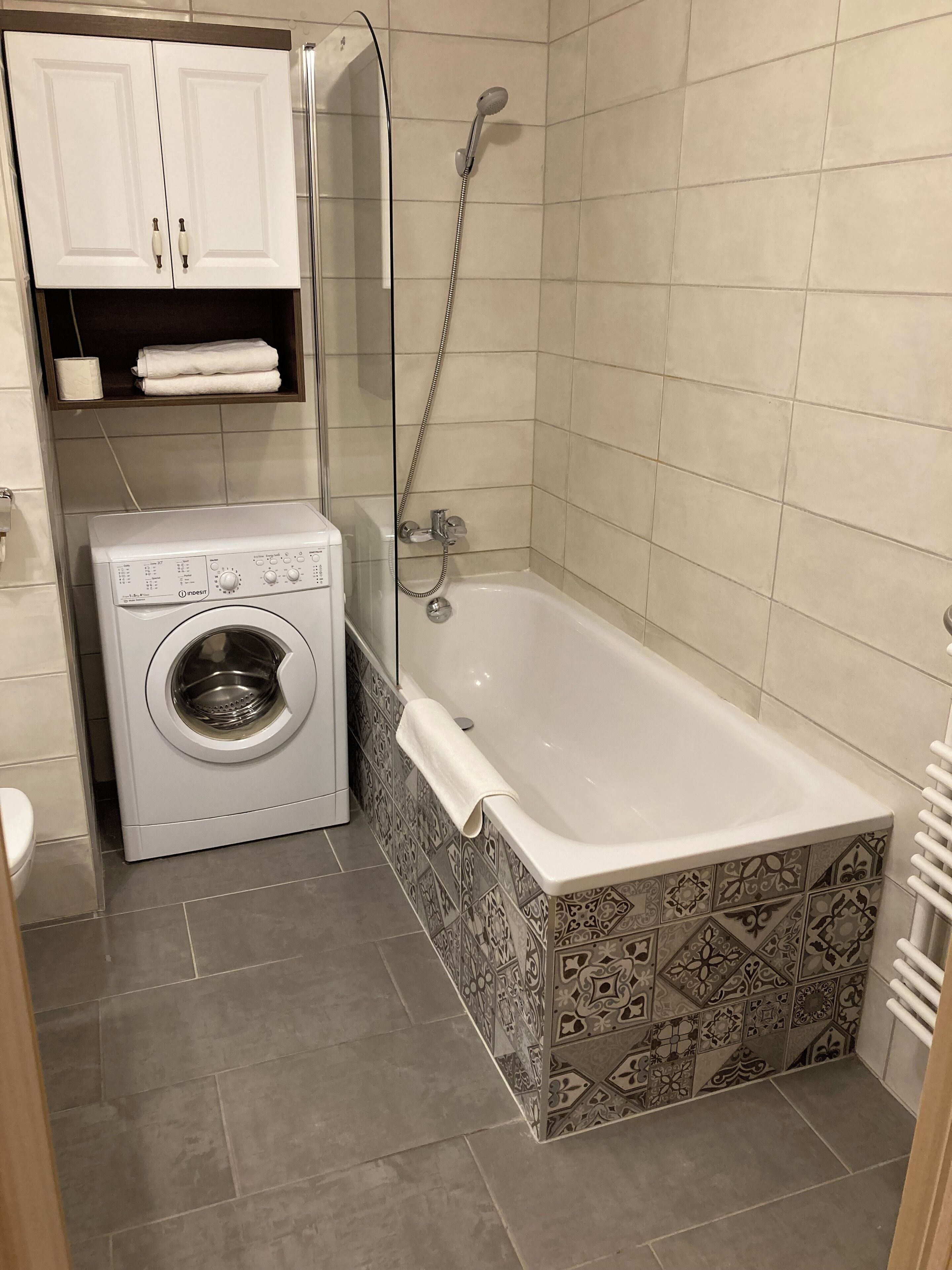 A compact bathroom with a washing machine, a shower, and a bathtub.
