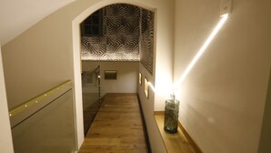 Un escalier avec un mur à motifs zébrés, une rampe en verre et un luminaire fixé au mur.