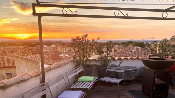 Terraza en la azotea con vistas a la puesta de sol, que incluye mobiliario exterior, una parrilla y plantas en macetas.