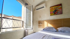 Un dormitorio con cama, ventana y aire acondicionado.
