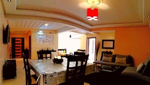 A dining area with a table set for four, a sofa, and a TV mounted on the wall. - Residence Tifaouine Agadir (Agadir)
