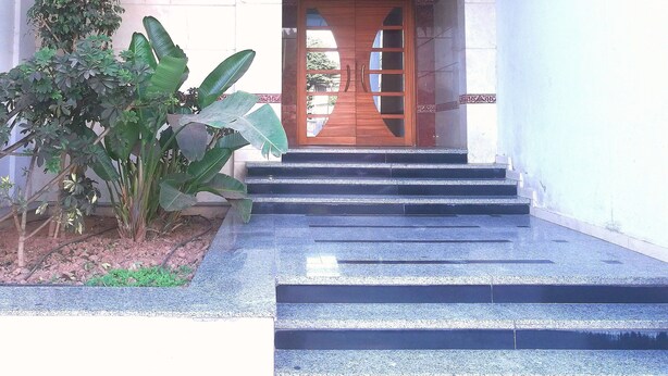 A building entrance with a wooden door, steps leading up to it, and a potted plant to the left. - Residence Tifaouine Agadir (Agadir)