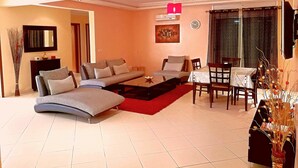 A living room with a sofa, coffee table, and dining area with chairs and a table. - Residence Tifaouine Agadir (Agadir)