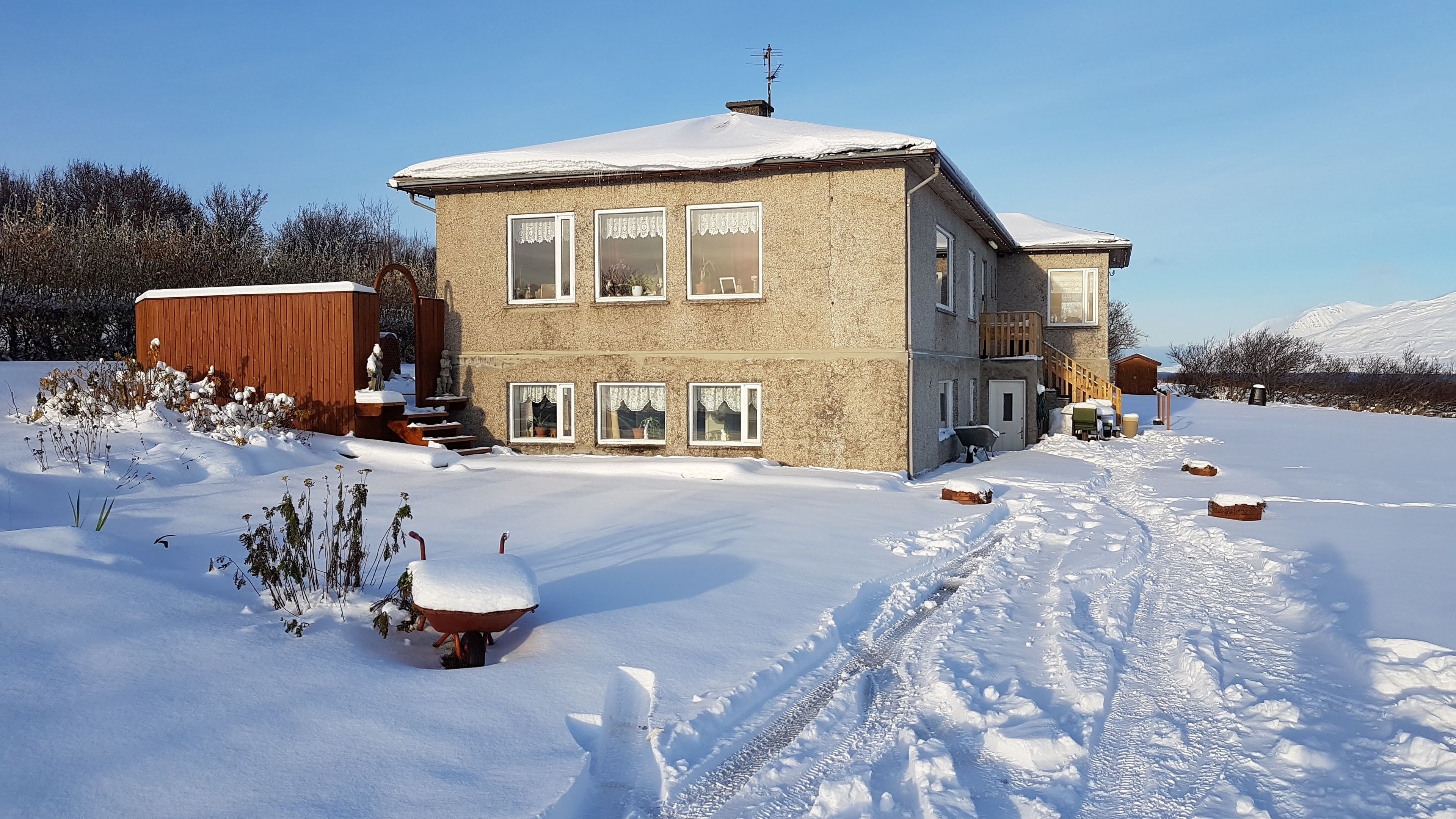 Una casa de dos pisos con tejado nevado y cielo despejado.