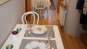 A dining area with a table set for two, chairs, a chandelier, and framed pictures on the wall. - The Viking Country Club (Hjalteyri)