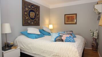 A neatly made bed with a white duvet, blue and white pillows, and a decorative headboard.