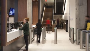 A modern lobby with a reception desk, a staircase, and turnstiles. - Parkside Student Residence (Toronto)