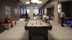A pool table in a modern room with abstract art on the walls, comfortable seating, and a casual atmosphere. - Parkside Student Residence (Toronto)