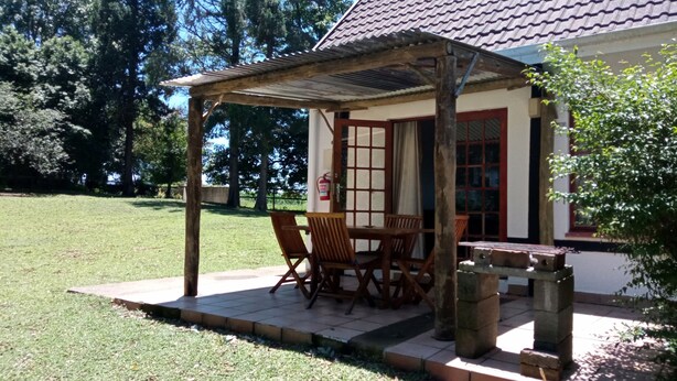 Un espacio de estar al aire libre cubierto con una mesa, sillas, un extintor y un banco de piedra.