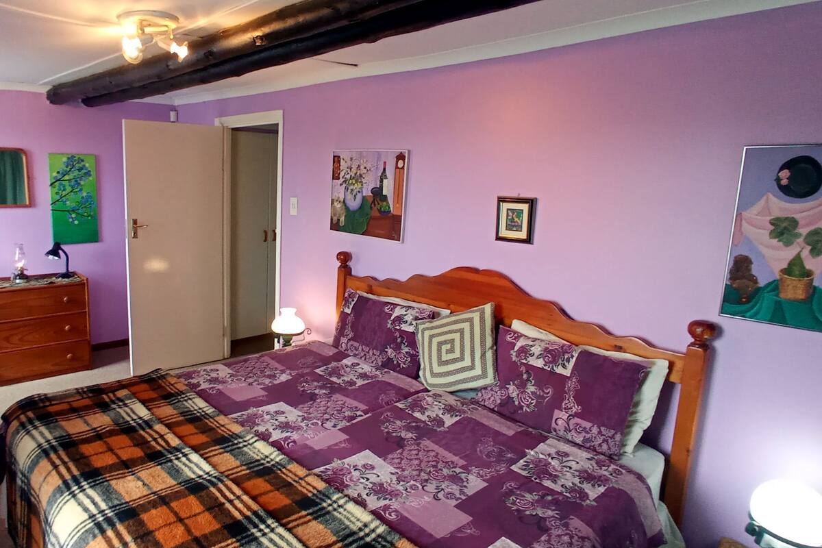 Quarto com cama, cômoda e obras de arte nas paredes.