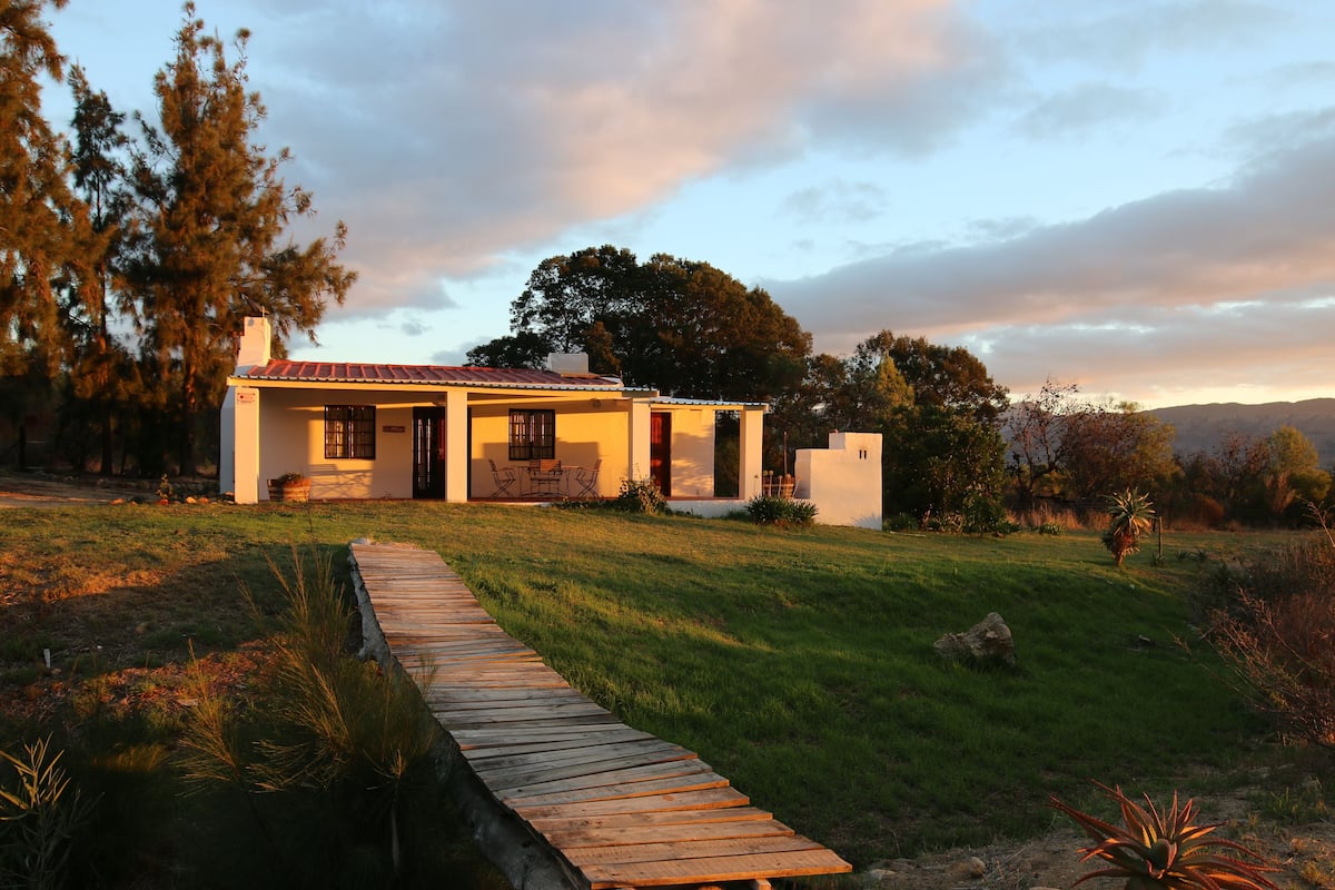 A single-story house with a covered porch, a wooden pathway leading to the entrance, and a grassy yard.
