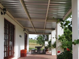 A covered outdoor area with a table and benches, a door, and potted plants.