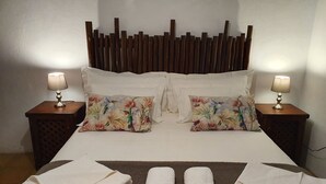 A neatly made bed with floral pillows, two bedside tables with lamps, and a brown rug. - Fraaigelegen Farm (Tulbagh)