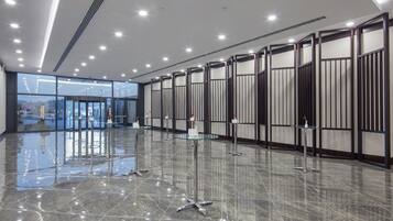 Un vestíbulo amplio con un piso de mármol pulido, puertas de vidrio que dan al exterior y un techo moderno con iluminación empotrada.