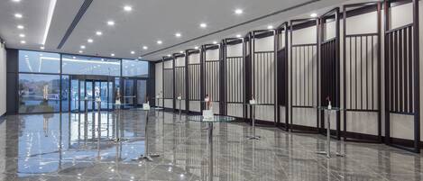 A spacious lobby with a polished marble floor, glass doors leading outside, and a modern ceiling with recessed lighting.