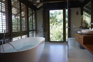 Casa de banho moderna com banheira independente, chuveiro e toucador com lavatório e espelho.