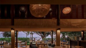 Een restaurant met houten vloeren, tafels en stoelen, met uitzicht op een waterpartij.