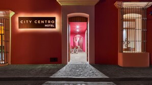 A hotel entrance with a sign reading "CITY CENTRO HOTEL," a pathway leading to the interior, and a bicycle parked inside. - City Centro by Marriott Oaxaca (Oaxaca)