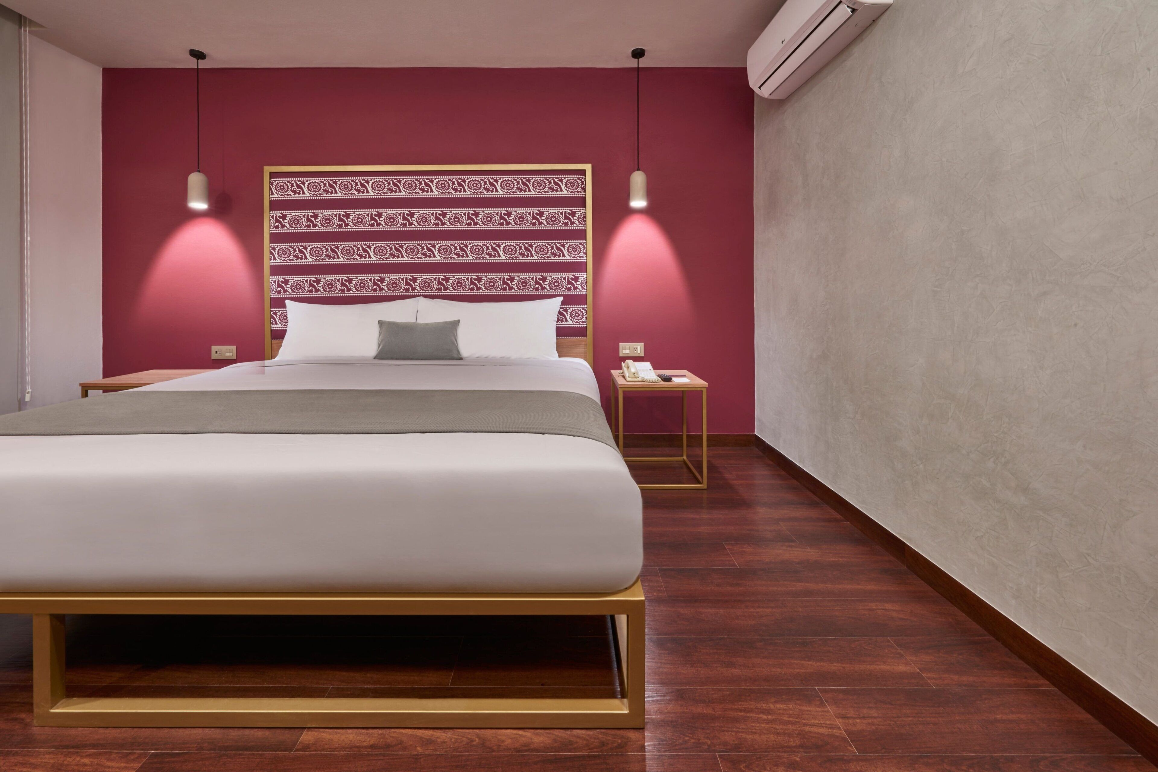 Une chambre d’hôtel moderne avec un grand lit, une tête de lit à motifs et deux tables de chevet.
