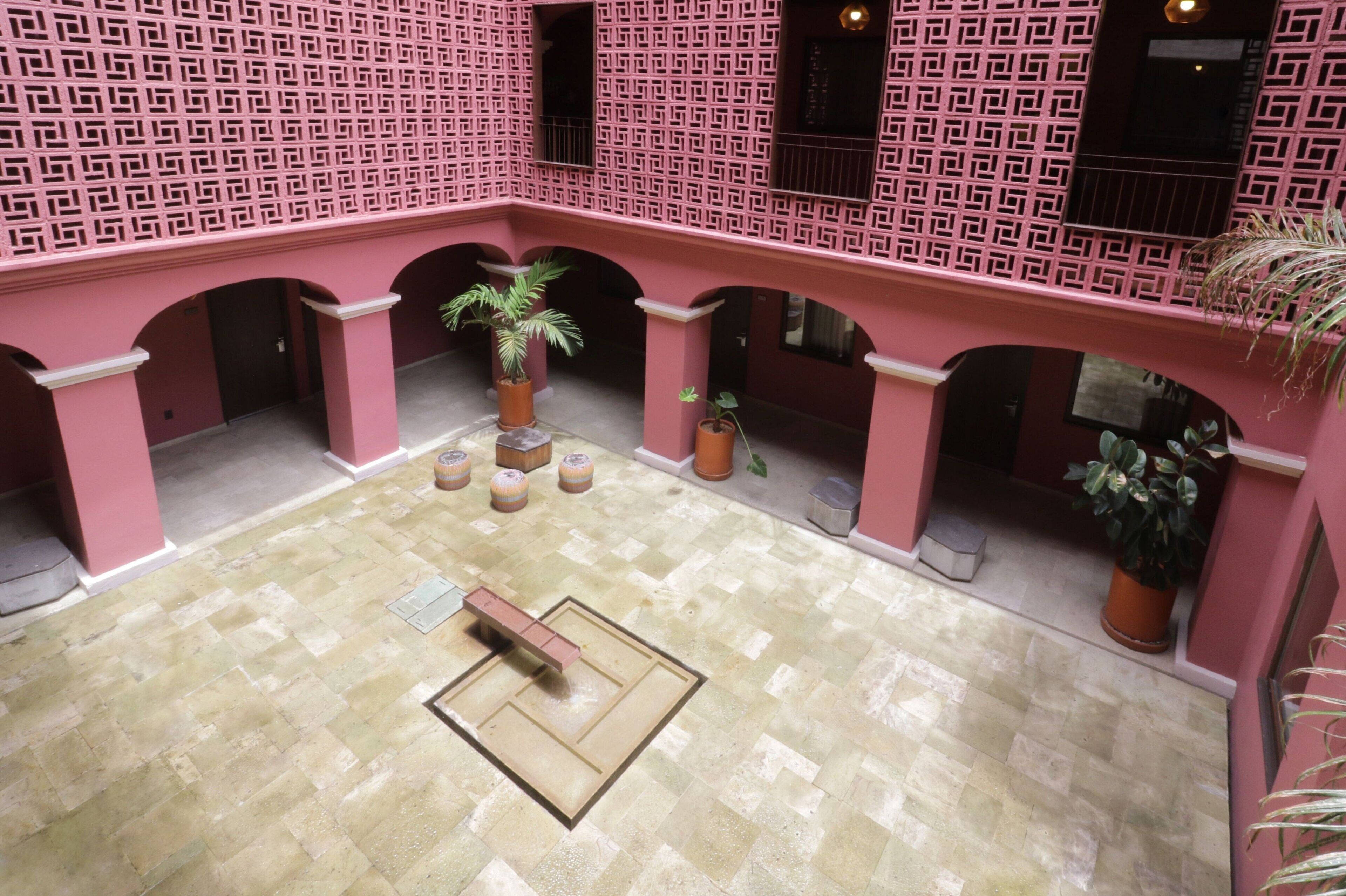 A courtyard with a tiled floor, pink walls, and a central seating area.