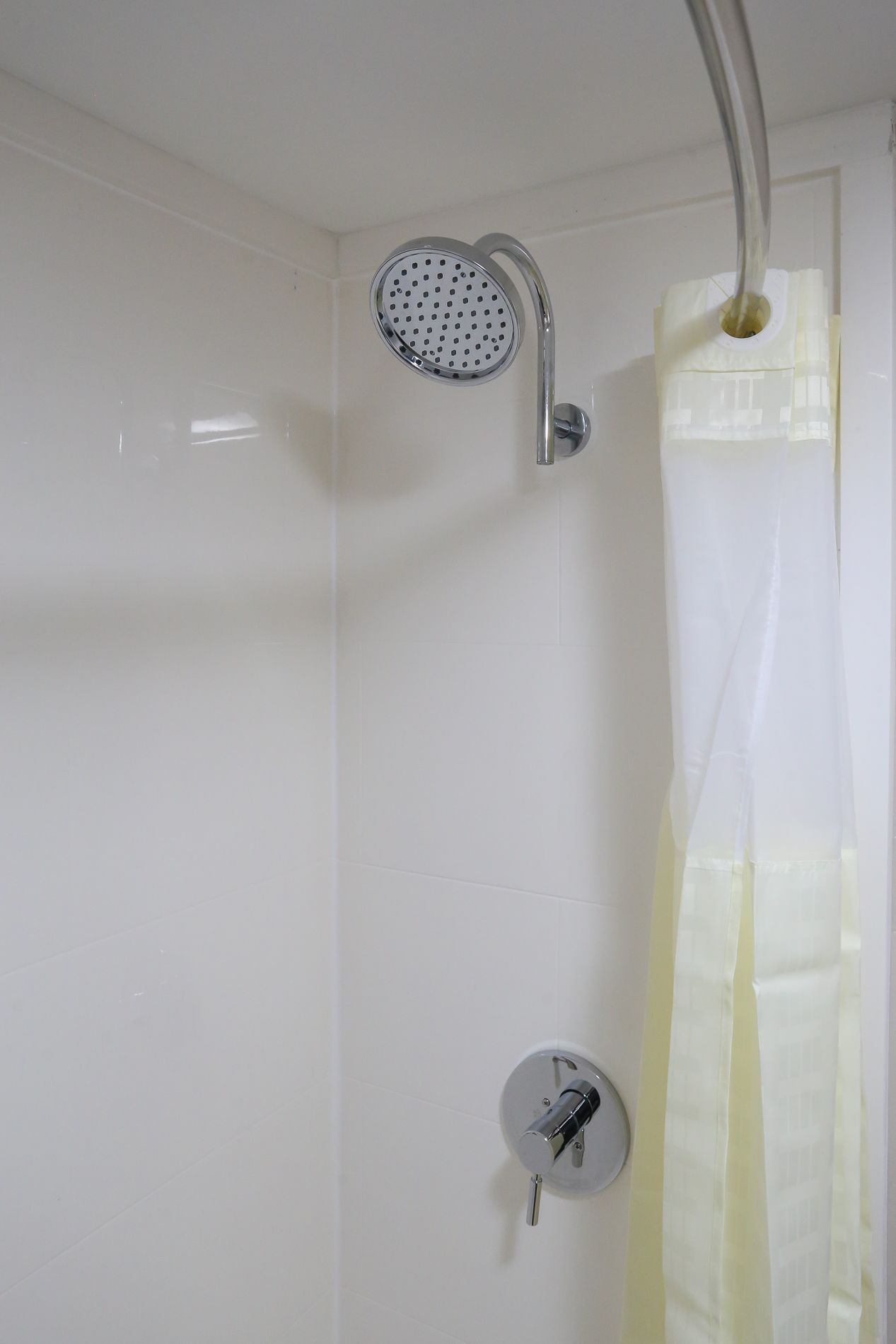 A shower with a handheld showerhead and a wall-mounted control.