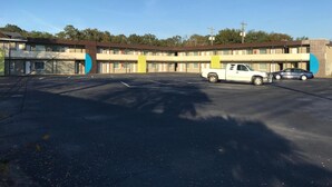 Un motel con aparcamiento, una camioneta blanca y un coche estacionados al frente.