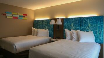 A hotel room with two beds, a wall art piece, and a modern headboard.