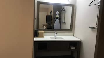 Un baño con lavabo, espejo y perchero para toallas.