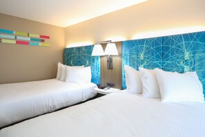 A hotel room with two beds, a nightstand with a clock, and a wall with a geometric pattern.